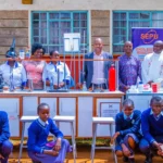 MP Machua Waithaka poses with education leaders and students next to mobile lab setups.