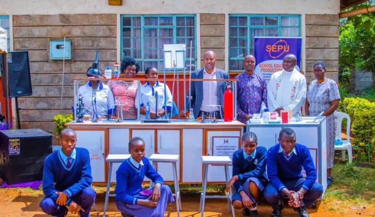 MP Machua Waithaka poses with education leaders and students next to mobile lab setups.