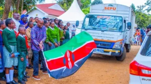 MP Machua Waithaka stands with students as the SEPU truck delivers mobile lab equipment.