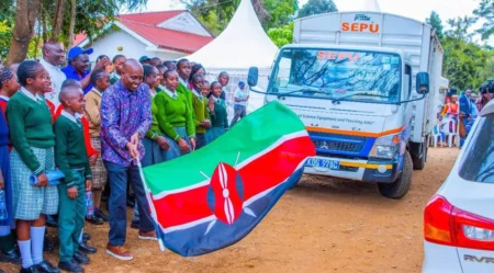 MP Machua Waithaka stands with students as the SEPU truck delivers mobile lab equipment.